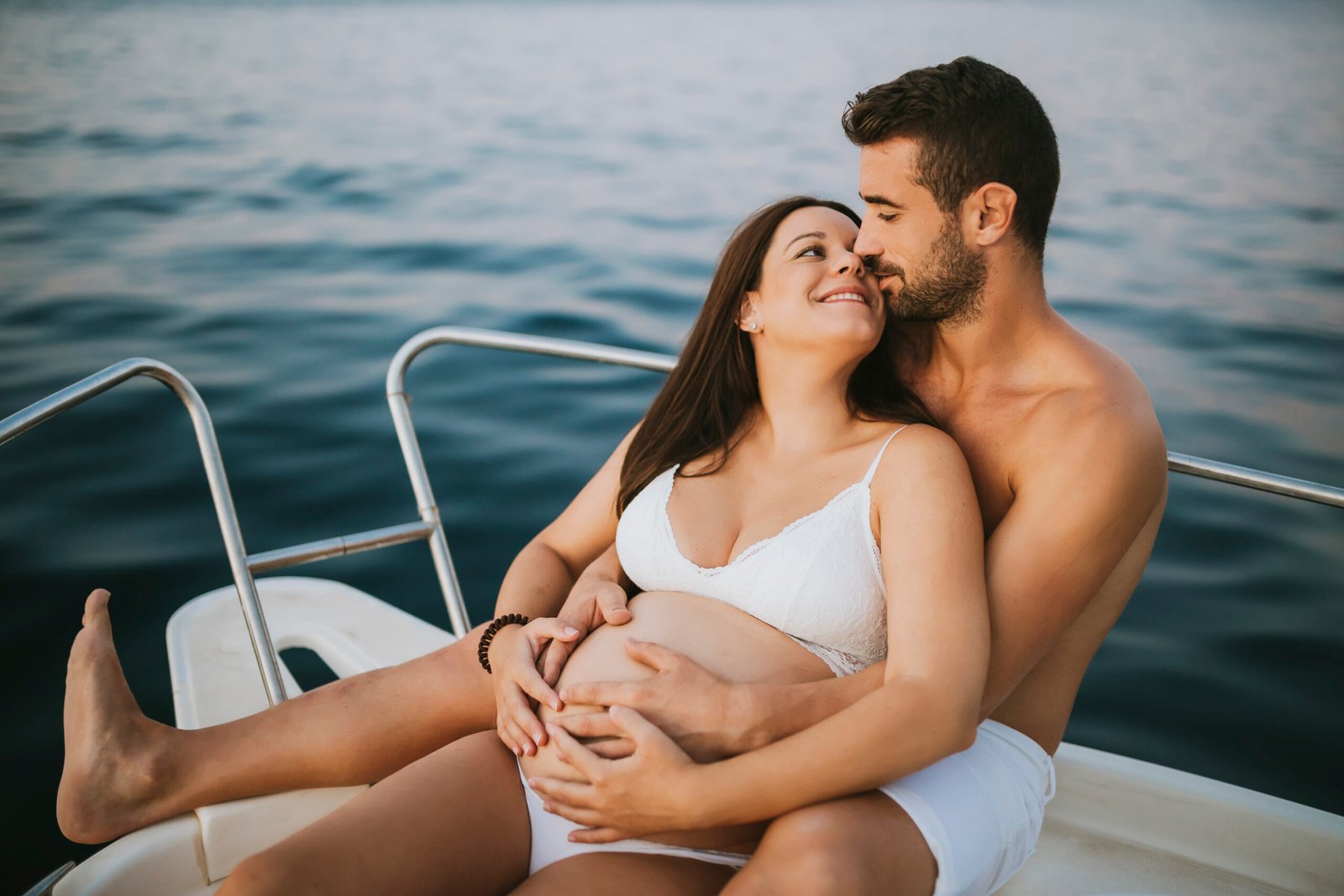 a Couple in a boat the woman is pregnant and the man is hugging her while they are on their way to Tiran Island